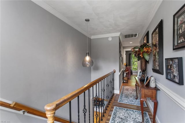 corridor featuring wood finished floors, crown molding, and baseboards