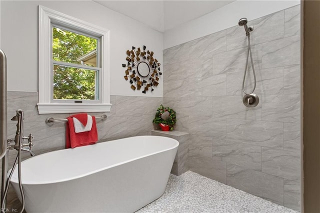 bathroom with tile walls, tiled shower, a freestanding tub, and a wainscoted wall
