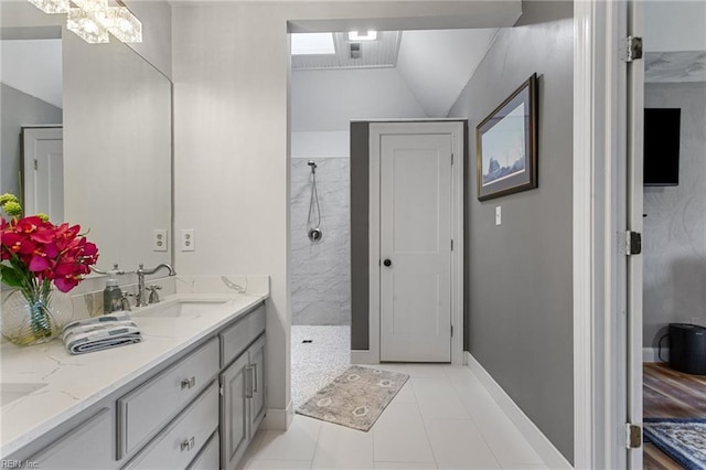 full bath with walk in shower, vanity, baseboards, tile patterned flooring, and vaulted ceiling