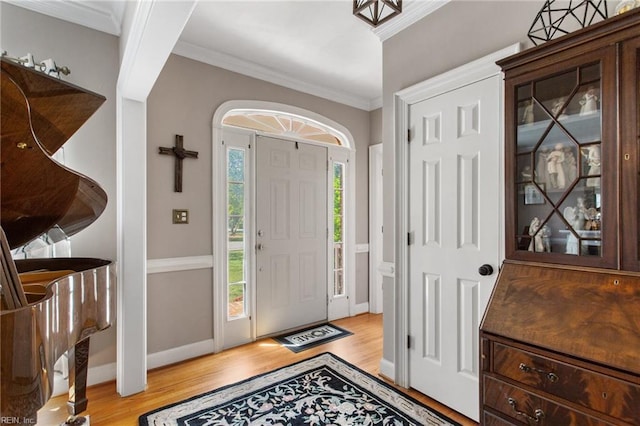 entrance foyer featuring light wood-type flooring, crown molding, and baseboards