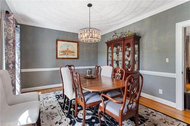 dining room featuring a chandelier, wood finished floors, baseboards, and ornamental molding