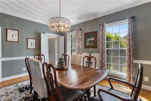 dining room with wood finished floors, plenty of natural light, a chandelier, and ornamental molding