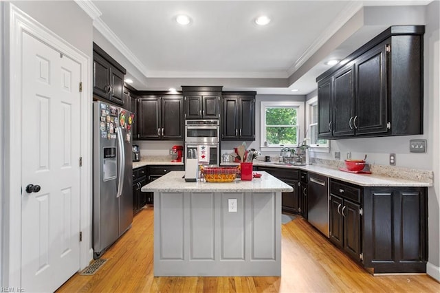 kitchen with appliances with stainless steel finishes, a center island, light wood-type flooring, ornamental molding, and recessed lighting