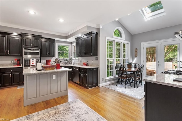 kitchen featuring stainless steel appliances, light wood-style floors, plenty of natural light, a skylight, and lofted ceiling