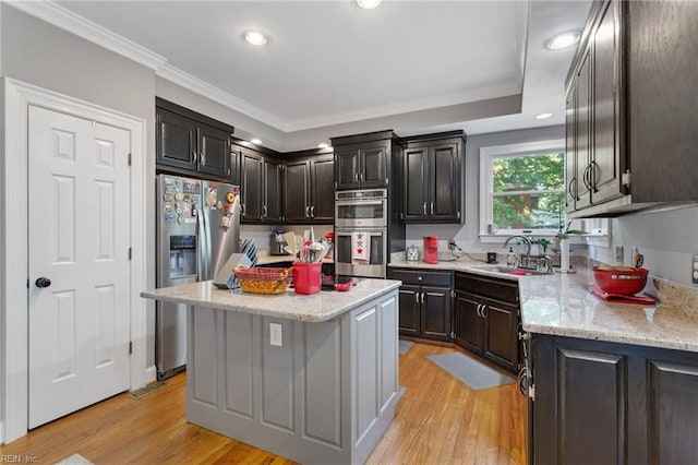 kitchen featuring stainless steel appliances, a center island, a sink, ornamental molding, and recessed lighting