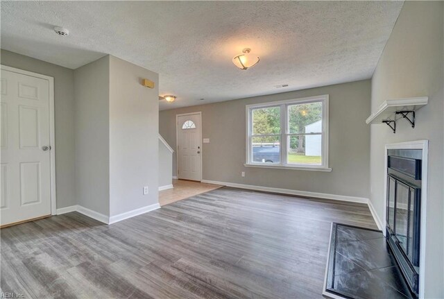 913 Fluvanna Rd, Newport News, VA 23601 - unfurnished living room with a textured ceiling, wood finished floors, baseboards, and a glass covered fireplace