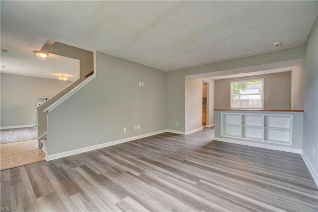 913 Fluvanna Rd, Newport News, VA 23601 - unfurnished living room with a textured ceiling, wood finished floors, baseboards, and stairs