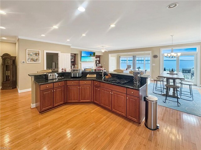 564 Riverside Dr, Lancaster, VA 22503 - kitchen featuring light wood-style flooring, ornamental molding, a chandelier, a kitchen island, and decorative light fixtures