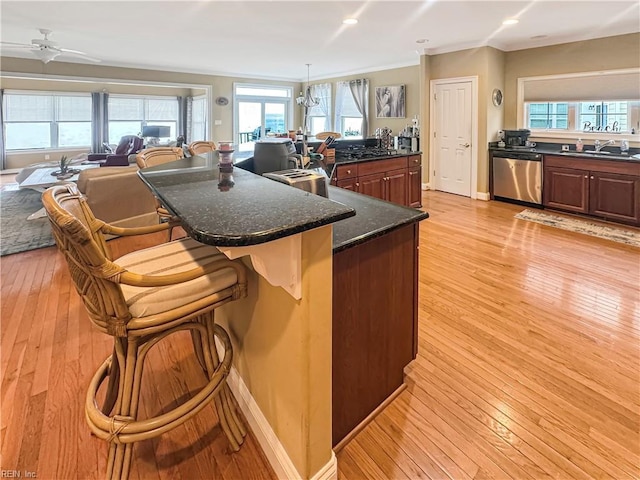 564 Riverside Dr, Lancaster, VA 22503 - kitchen with stainless steel dishwasher, a sink, light wood-style flooring, a kitchen breakfast bar, and crown molding
