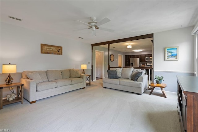 living room featuring light carpet, ceiling fan, and baseboards