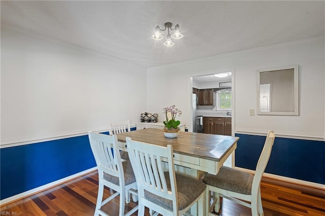 dining room featuring a chandelier, wood finished floors, ornamental molding, and baseboards