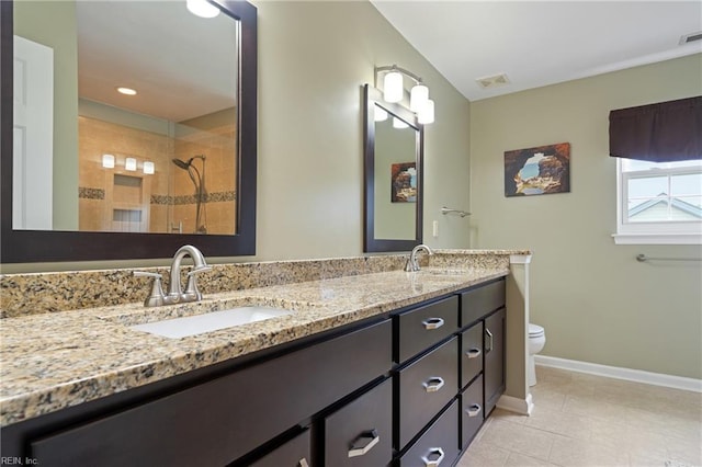 full bathroom with baseboards, tile patterned flooring, tiled shower, double vanity, and toilet
