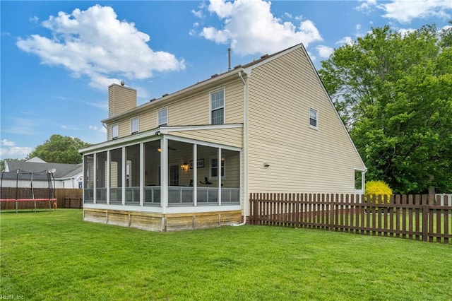 rear view of house featuring a trampoline, a sunroom, and a chimney