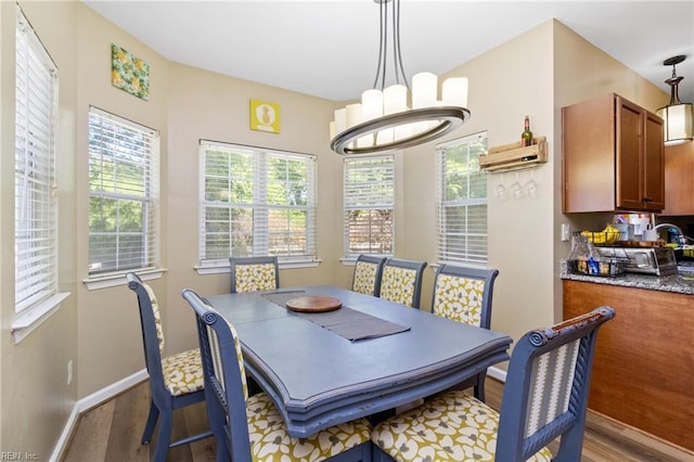 dining space featuring wood finished floors, baseboards, and a chandelier