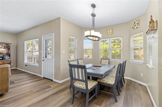 dining room featuring light wood-type flooring, healthy amount of natural light, a chandelier, and baseboards