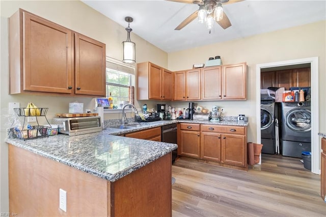 kitchen with separate washer and dryer, a sink, black dishwasher, light stone counters, and a ceiling fan