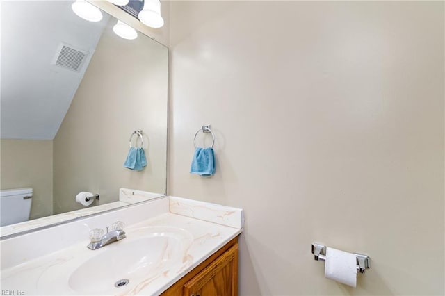 half bathroom featuring toilet, vanity, and lofted ceiling