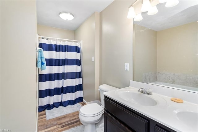 bathroom with double vanity, toilet, a shower with curtain, and wood finished floors