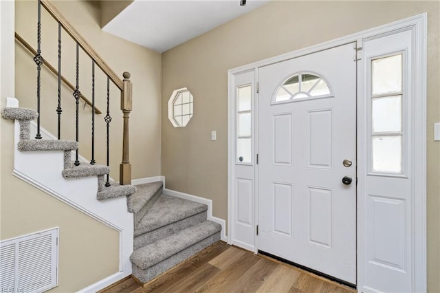 foyer featuring wood finished floors, stairs, and baseboards