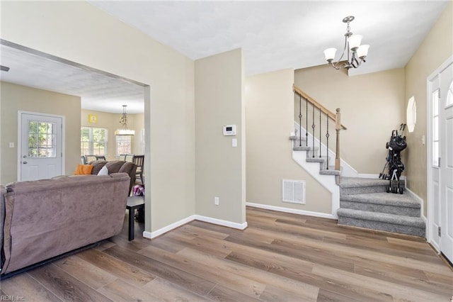 foyer with a chandelier, wood finished floors, stairs, and baseboards