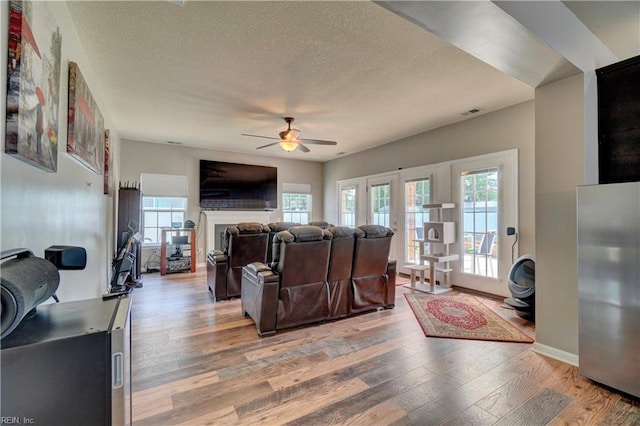 6884 Emerson Ln, Hayes, VA 23072 - living room with ceiling fan, light wood finished floors, plenty of natural light, a textured ceiling, and a fireplace