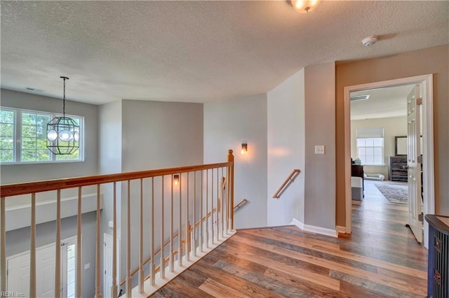 6884 Emerson Ln, Hayes, VA 23072 - hallway featuring an upstairs landing, wood finished floors, a textured ceiling, a chandelier, and baseboards