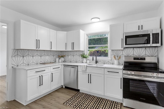 1304 Woodcrest Dr, Hampton, VA 23663 - kitchen featuring appliances with stainless steel finishes, a sink, white cabinets, light wood-style floors, and decorative backsplash