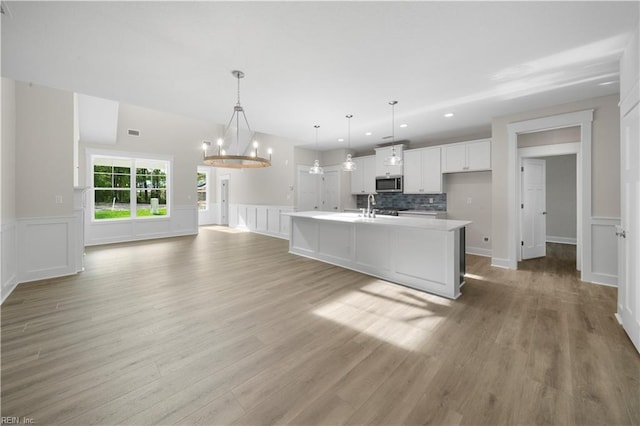2094 Asher Dr, Suffolk, VA 23435 - kitchen featuring stainless steel microwave, white cabinets, light countertops, a center island with sink, and light wood-type flooring