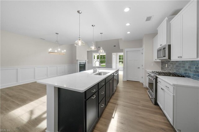 2094 Asher Dr, Suffolk, VA 23435 - kitchen featuring stainless steel appliances, a sink, white cabinets, tasteful backsplash, and a center island with sink