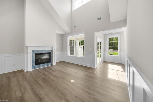 2094 Asher Dr, Suffolk, VA 23435 - unfurnished living room featuring a wainscoted wall, a high ceiling, a glass covered fireplace, wood finished floors, and a decorative wall