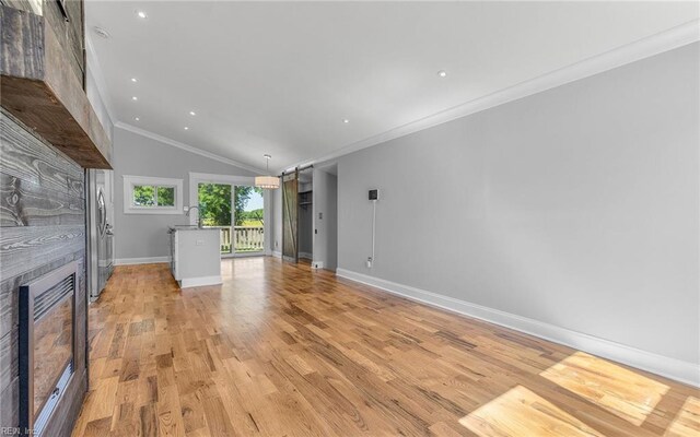 147 Ransone St, Hampton, VA 23669 - unfurnished living room featuring a glass covered fireplace, vaulted ceiling, light wood finished floors, baseboards, and ornamental molding