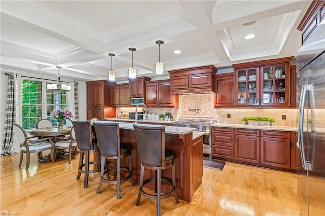 kitchen featuring high quality appliances, coffered ceiling, light wood-type flooring, a kitchen breakfast bar, and pendant lighting