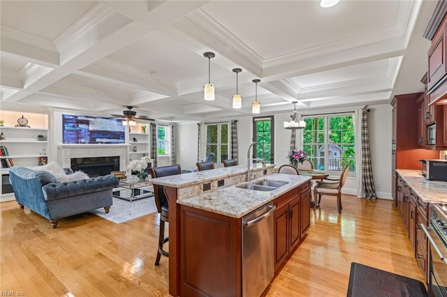 kitchen featuring a sink, stainless steel dishwasher, a kitchen breakfast bar, a ceiling fan, and plenty of natural light