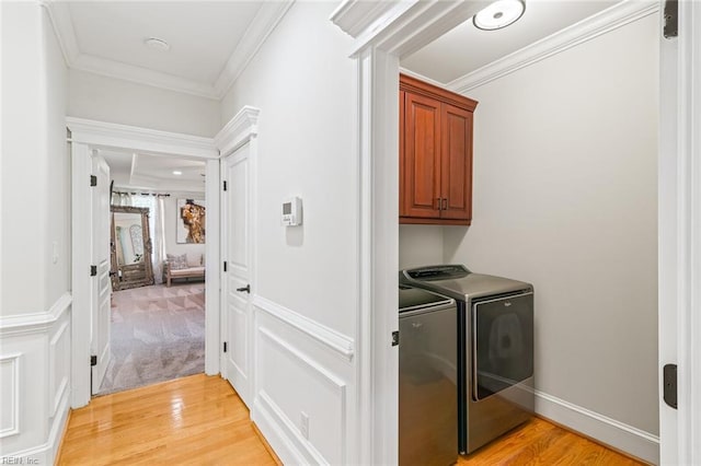 washroom with independent washer and dryer, cabinet space, light wood-style flooring, and ornamental molding