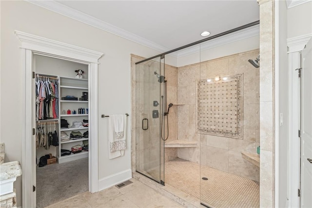 bathroom featuring crown molding, a stall shower, a walk in closet, and baseboards