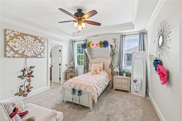 bedroom featuring a tray ceiling, ornamental molding, light carpet, baseboards, and a ceiling fan