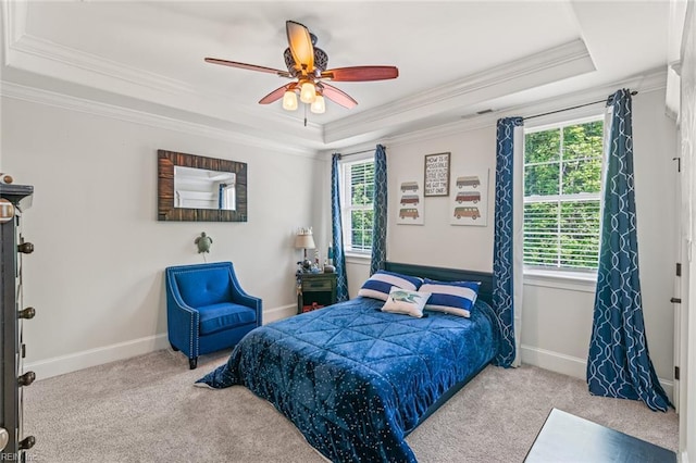 bedroom with a tray ceiling, carpet, ornamental molding, baseboards, and a ceiling fan