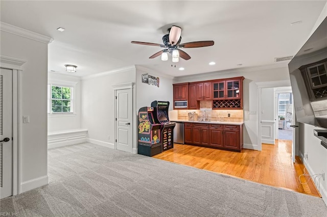 kitchen with a ceiling fan, appliances with stainless steel finishes, crown molding, a sink, and backsplash