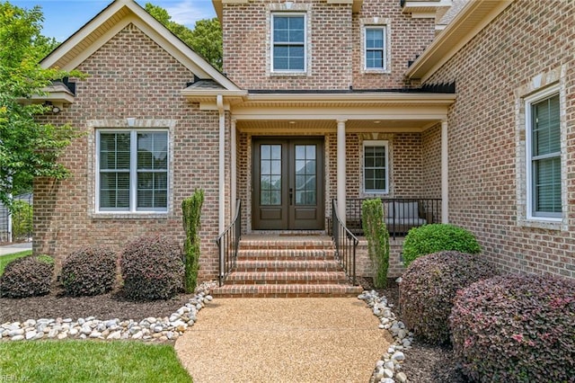 property entrance featuring french doors, brick siding, and a porch