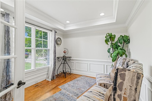 sitting room featuring healthy amount of natural light, crown molding, wood finished floors, recessed lighting, and a tray ceiling