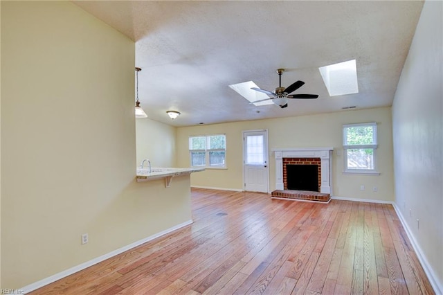 536 Willow Bend Dr, Chesapeake, VA 23323 - unfurnished living room featuring a skylight, light wood-style flooring, a fireplace, plenty of natural light, and a textured ceiling