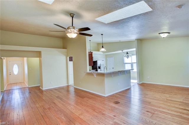 536 Willow Bend Dr, Chesapeake, VA 23323 - kitchen featuring a skylight, a breakfast bar area, stainless steel fridge with ice dispenser, light wood-type flooring, and a textured ceiling