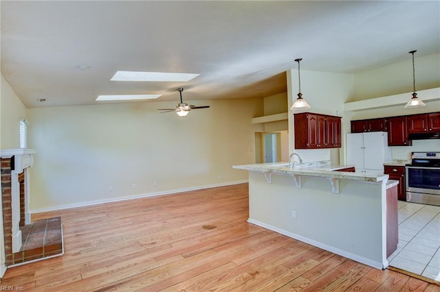 536 Willow Bend Dr, Chesapeake, VA 23323 - kitchen with stainless steel electric range oven, under cabinet range hood, white refrigerator, reddish brown cabinets, and a skylight