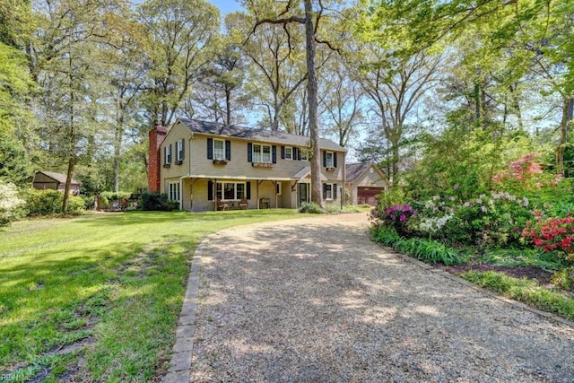 view of front of house with a chimney, a front yard, and driveway