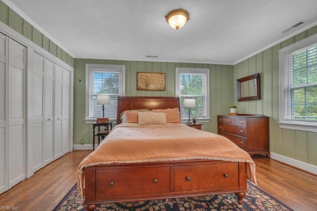 bedroom featuring wood finished floors, ornamental molding, and baseboards