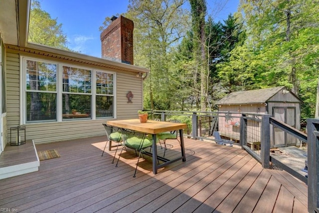 wooden terrace featuring a storage shed, an outbuilding, and outdoor dining space