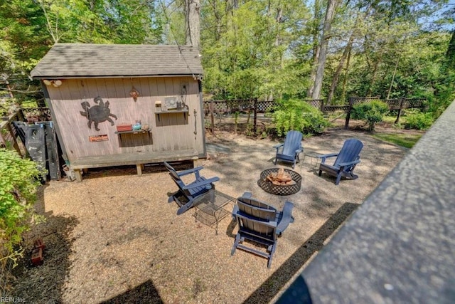 view of patio with an outdoor fire pit, fence, and an outdoor structure