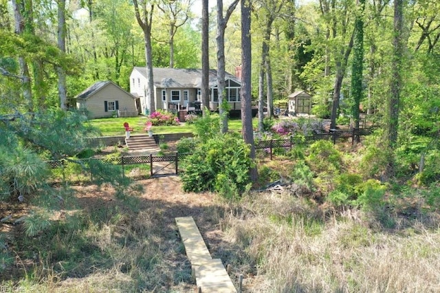 fenced backyard with a forest view, an outbuilding, a storage shed, and a wooden deck