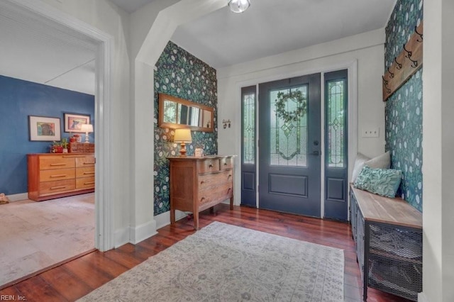 foyer with wallpapered walls, wood finished floors, and baseboards