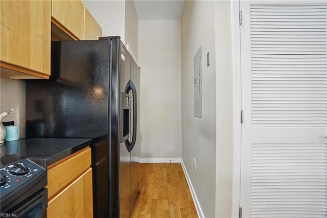 388 Boush St Unit 122, Norfolk, VA 23510 - kitchen featuring light wood-style flooring, dark countertops, baseboards, black fridge, and electric panel